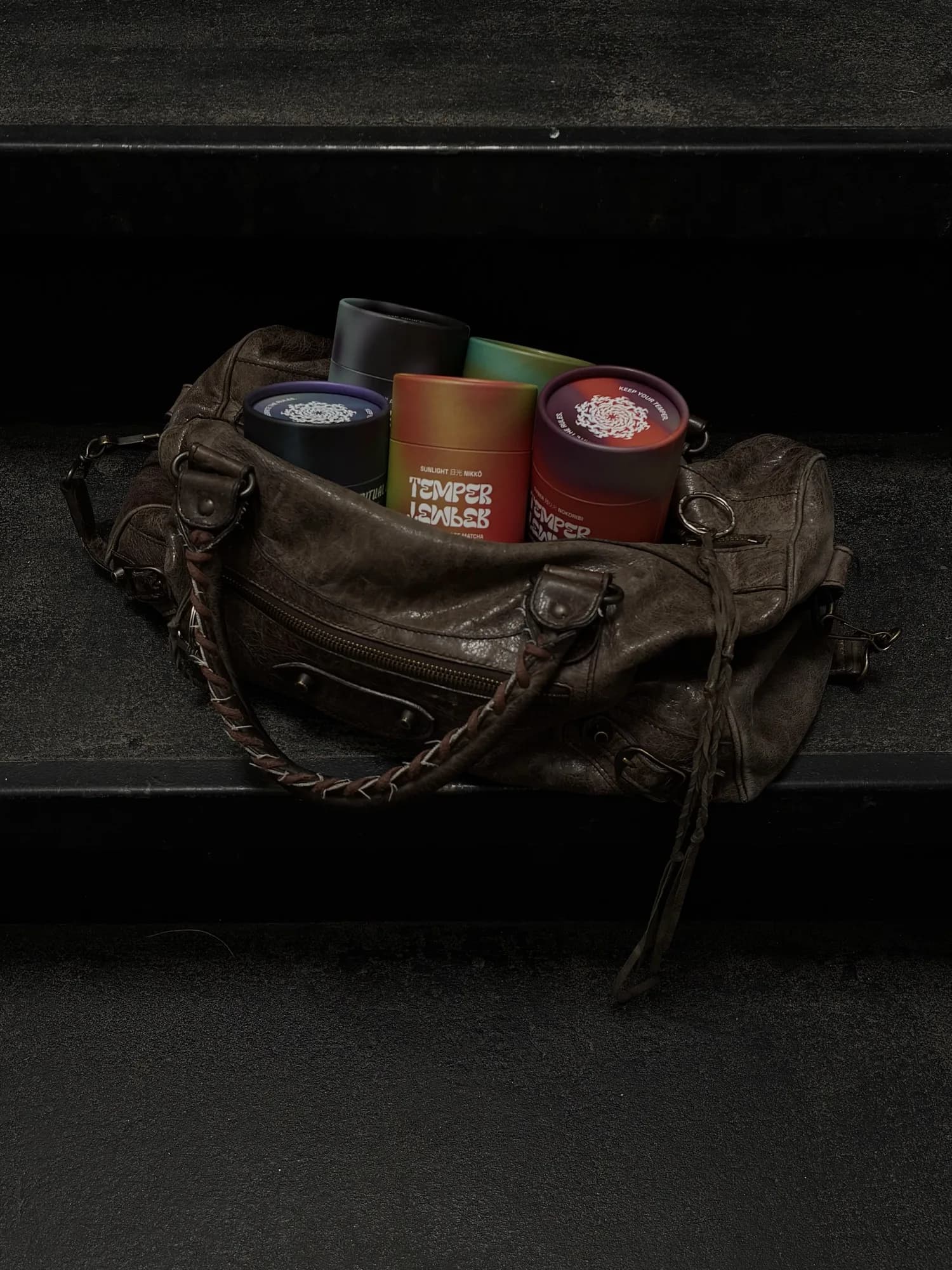 Temper Temper tins spilling from a leather bag